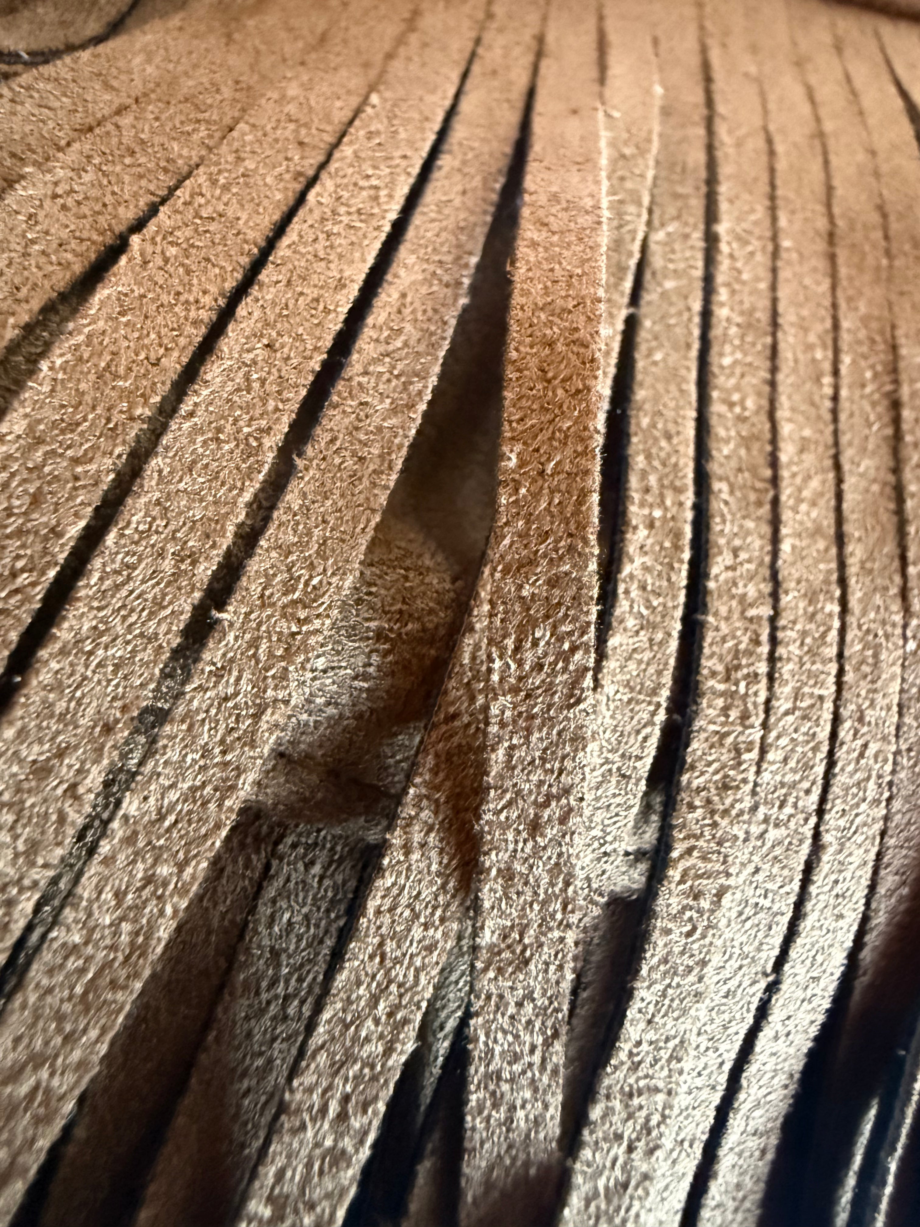 A closeup crop of suede fringe from a handbag