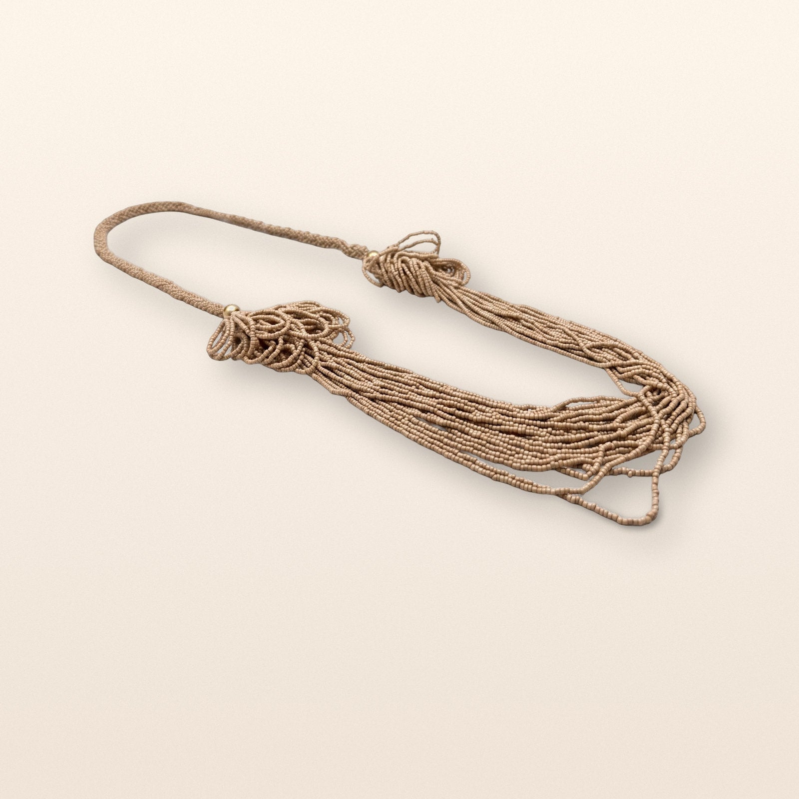 Layered beaded necklace arranged against a warm neutral background.